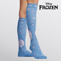 Nurse wearing cornflower blue Disney Frozen knee-high compression socks printed with Elsa portraits and snowflake motifs, featuring the official "Disney FROZEN" logo overhead and "WOOF" top cuff branding.