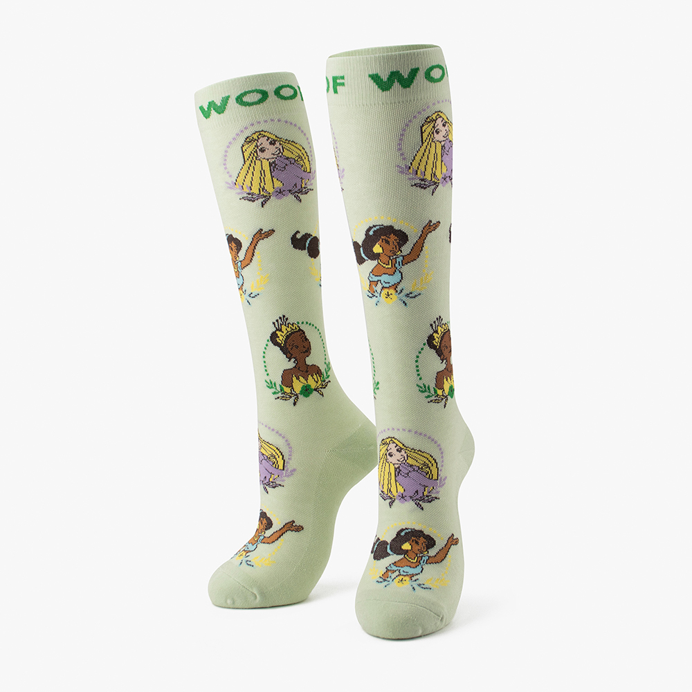 Side-by-side standing display of the mint green Disney Princess character portrait knee-high compression socks featuring Rapunzel, Tiana, Moana, and Cinderella.