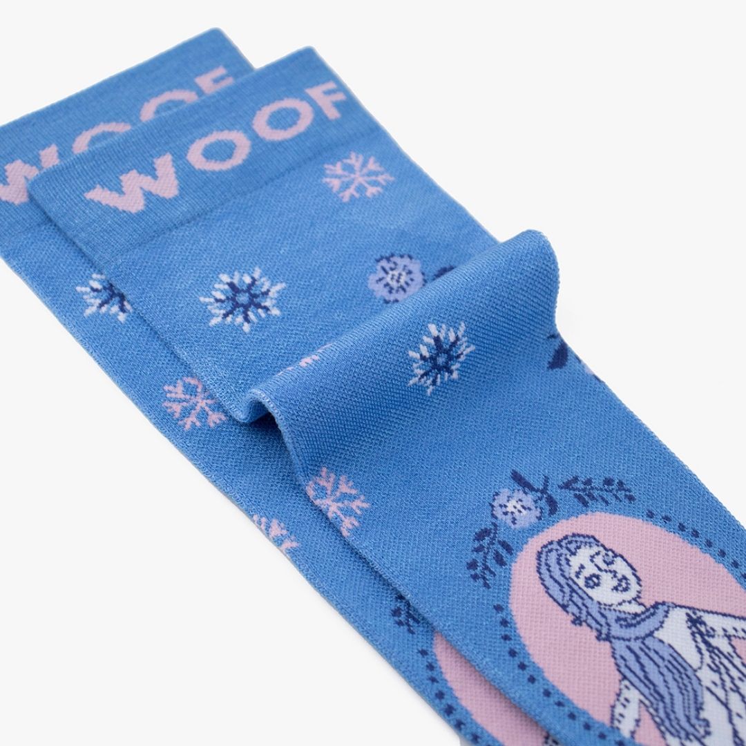 Folded view of cornflower blue knee-high compression socks displaying the Disney Frozen Elsa portrait and snowflake pattern alongside the "WOOF" top cuff tag.